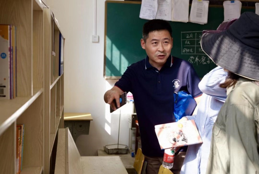 在大莫村弄關民族小學圖書室，與扶貧采風團探討鄉(xiāng)村教育發(fā)展的中華文學基金會副秘書長安亞斌 攝影：趙衛(wèi)國